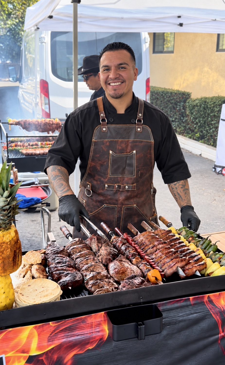 Chef CJ smiling behind a live grill station
